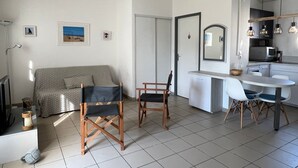 A compact living space with a kitchenette, a dining area with chairs, a sofa, and a television. - Holiday Home "52 Amareyeurs" close to the Sea with Shared Pool (Le Château-d'Oléron)