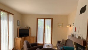 A living room with a television, two sofas, a fireplace, and a window with curtains. - Holiday Home "Pass Giraudière" with Terraces (LE GRAND VILLAGE PLAGE)