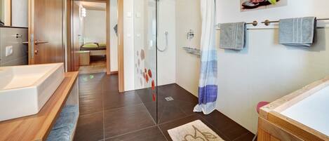 A modern bathroom with a glass shower enclosure, a bathtub, and a toilet.