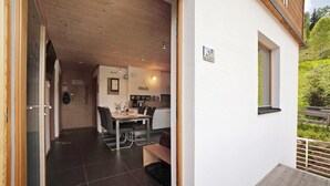 Ein Innenraum eines modernen Hauses mit Essbereich, Küche und einem Balkon mit Holzgeländer.
