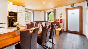 A dining area with a wooden table, chairs, and a bench. There is a kitchen area with a stove and a refrigerator. - Apartment 'Joshof Talblick' with Mountain View, Private Terrace and Wi-Fi (Moso in Passiria)