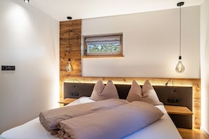 Une chambre moderne avec une tête de lit en bois, une table de chevet, une fenêtre avec vue et un luminaire suspendu.