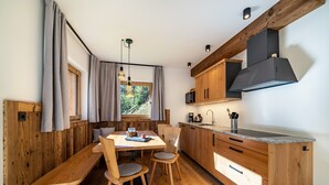 A modern kitchen with wooden cabinetry, a built-in stove, and a dining area with a bench and chairs. - Apartment "Grogg 608 I" with Mountain View, Garden & Wi-Fi (Martello)