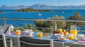 Una mesa con alimentos para el desayuno y vistas al mar y las montañas.