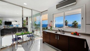 Una cocina moderna con vistas al mar, un comedor con sillas y un ventanal grande.
