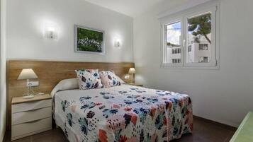 Ein Schlafzimmer mit einem Bett, zwei Nachttischen, einer Fensterlampe und einer Wandleuchte.