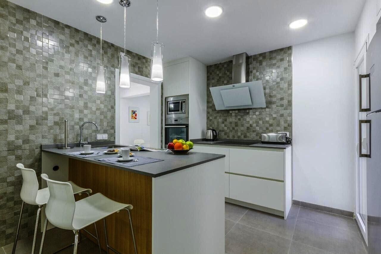Una cocina moderna con una isla central, armarios blancos, microondas y tostadora.