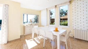 A bright room with a white table, chairs, and a window with a view of greenery.