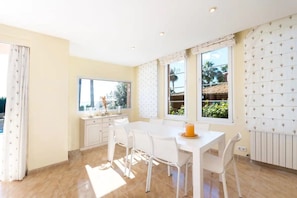 A bright room with a white table, chairs, and a window with a view of greenery.