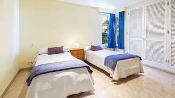 Une chambre avec deux lits, une table de chevet, une lampe et une armoire.