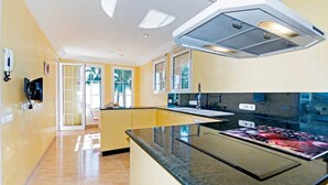 A modern kitchen with a central island, yellow walls, and a view of the outdoors.