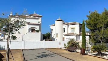 Un patio con suelo empedrado, un banco y un árbol alto.