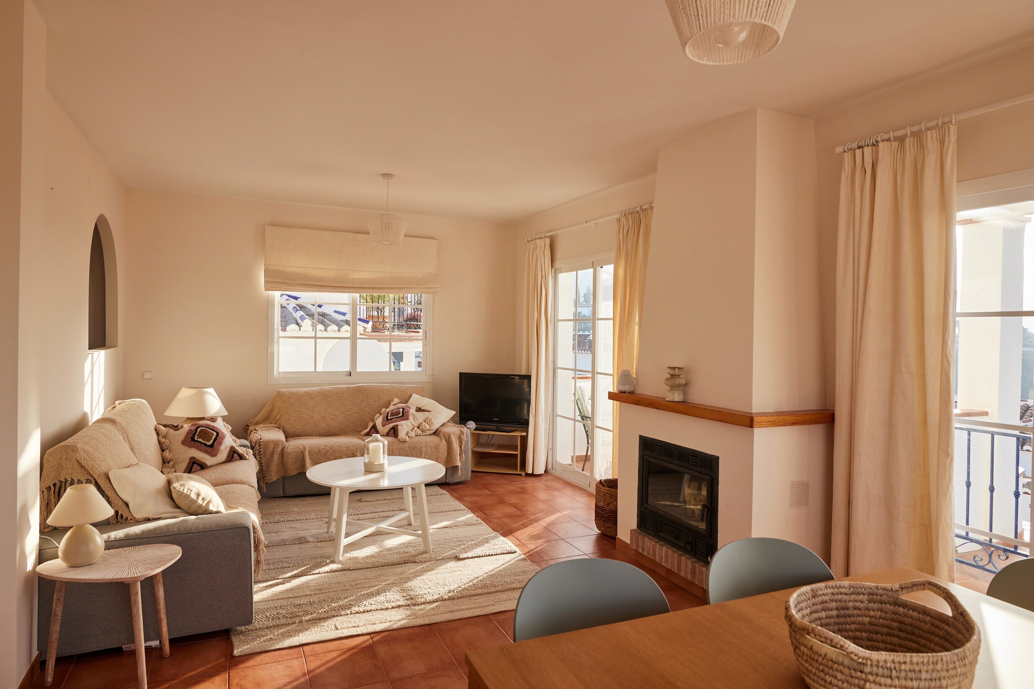 A living room with a sofa, a television, a fireplace, and a dining area.