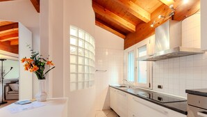 Una cocina moderna con armarios blancos, una campana extractora de acero inoxidable y un ventanal con vistas al exterior.