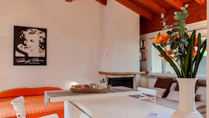 Una habitación con una cama, una mesa con una bandeja de comida, una chimenea y una ventana con una planta.