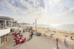 A beachside promenade with outdoor seating and a view of the beach.