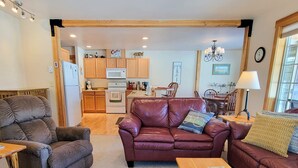 A living room with a leather sofa, wooden coffee table, and a dining area with wooden furniture. - Sunshine Station - 3 bedroom Winthrop Townhouse (Winthrop)