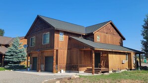 A two-story wooden house with a porch, a garage, and a small attached structure. - Sunshine Station - 3 bedroom Winthrop Townhouse (Winthrop)
