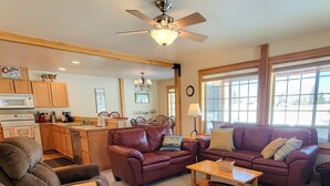 A living room with leather sofas, a coffee table, and a dining area with wooden cabinets and a microwave. - Sunshine Station - 3 bedroom Winthrop Townhouse (Winthrop)