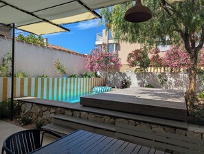 Un espace piscine agrĂ©mentĂ© dâun mur en pierre, dâune terrasse en bois et dâune lampe suspendue.