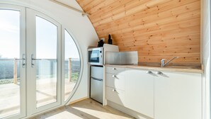 Una cocina moderna con techo de madera, microondas integrado y refrigerador de acero inoxidable.