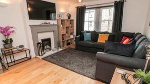 Un salon moderne avec une cheminée, un canapé, une table basse et un téléviseur fixé au mur.