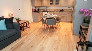 Une cuisine moderne avec des meubles en bois, un coin repas avec une table ronde et des chaises, et un salon avec un canapé et une table basse.