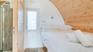 Een slaapkamer met een houten plafond, een bed met witte beddengoed en een deur naar een badkamer.