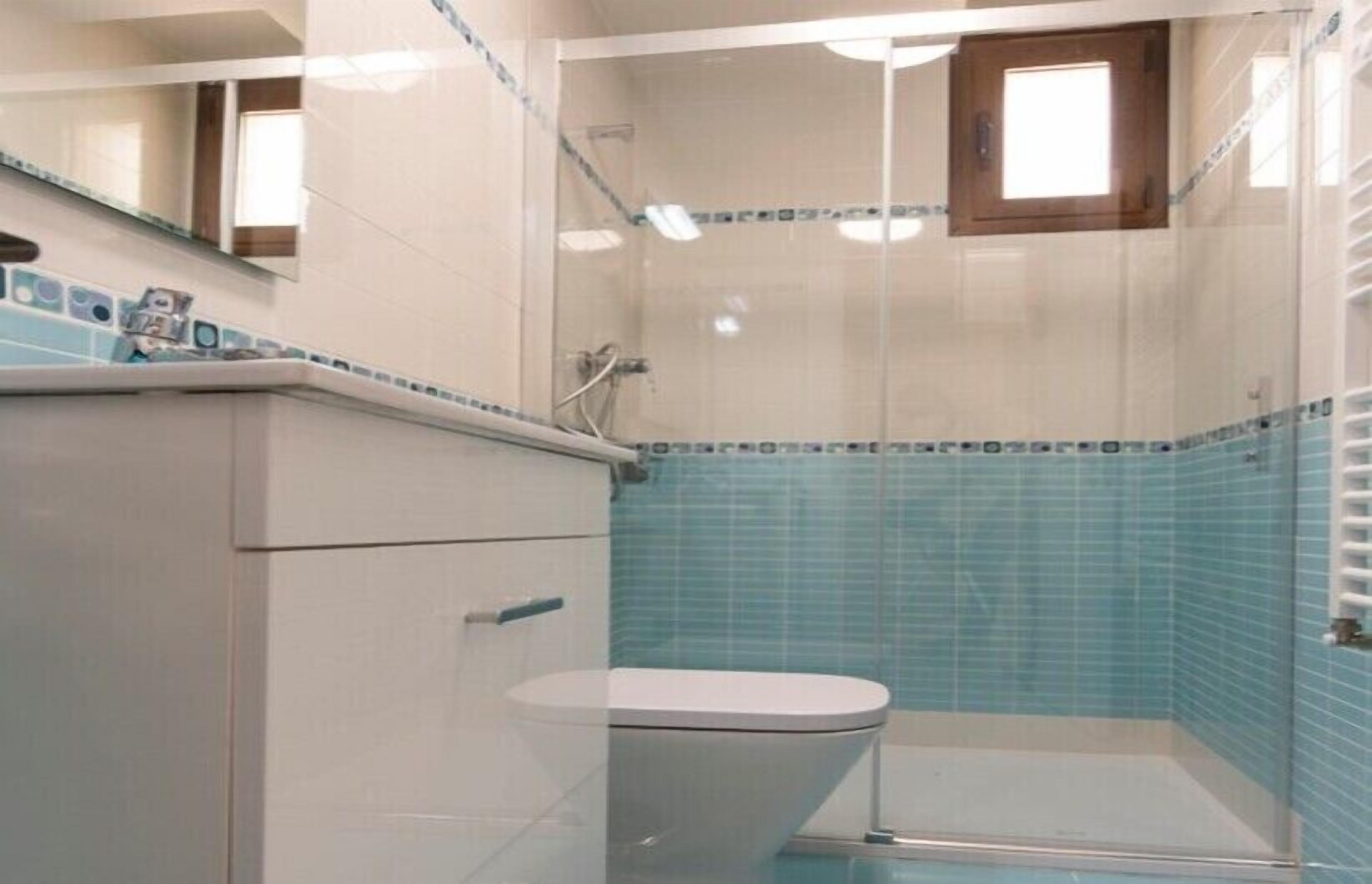 Une salle de bain avec une cabine de douche, des toilettes et un lavabo avec un miroir au-dessus.