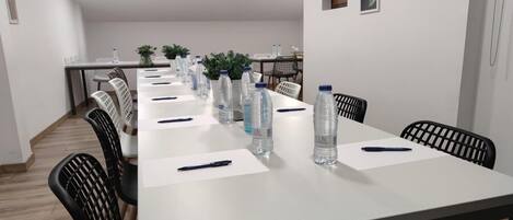 A conference room with a long table, chairs, water bottles, and pens.