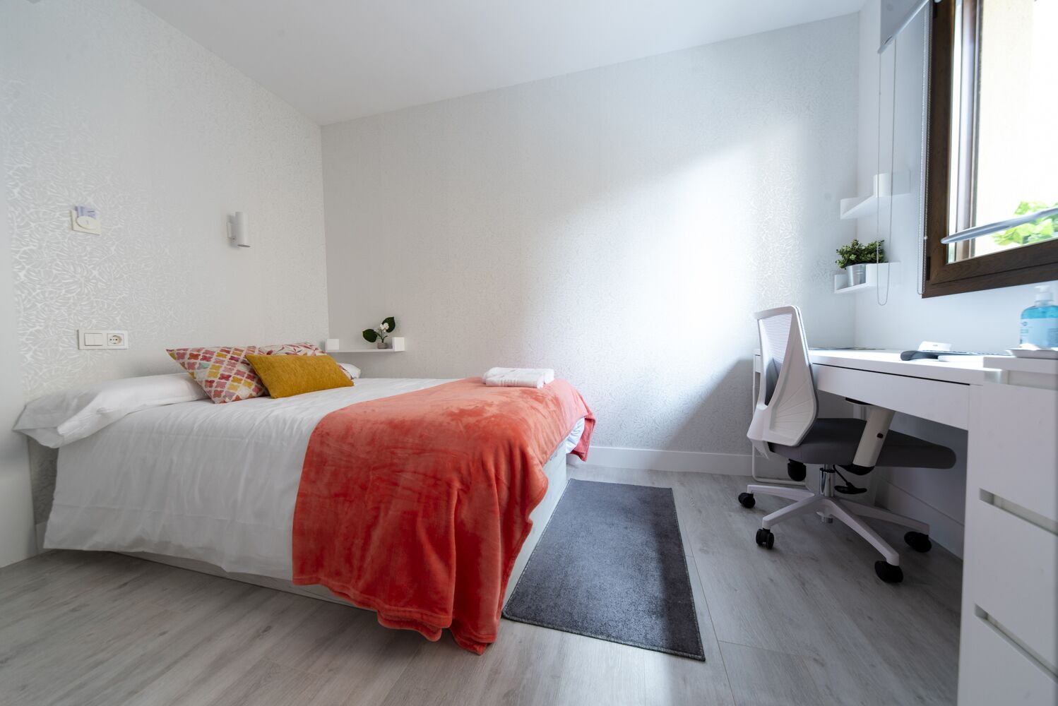 A modern bedroom with a bed, desk, and chair.