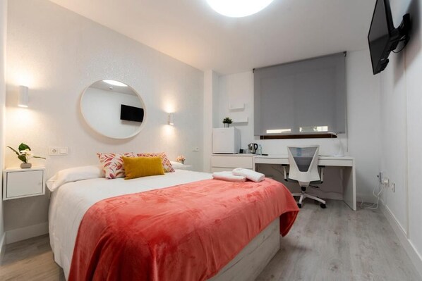 A modern bedroom with a bed, a desk, and a TV mounted on the wall. - Vizcainos Home Away (Segovia)