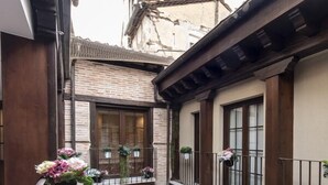 A courtyard with a tiled floor, a wooden balcony, and potted plants. - Vizcainos Home Away (Segovia)
