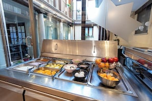 Una mesa de buffet con diversos alimentos y un bol de frutas.