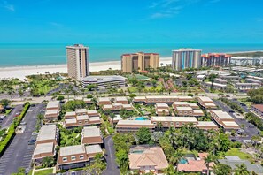 A resort area with multiple buildings, a parking lot, and a beach in the background. - Quaint Condo | Steps to the Beach and Dining (Marco Island)