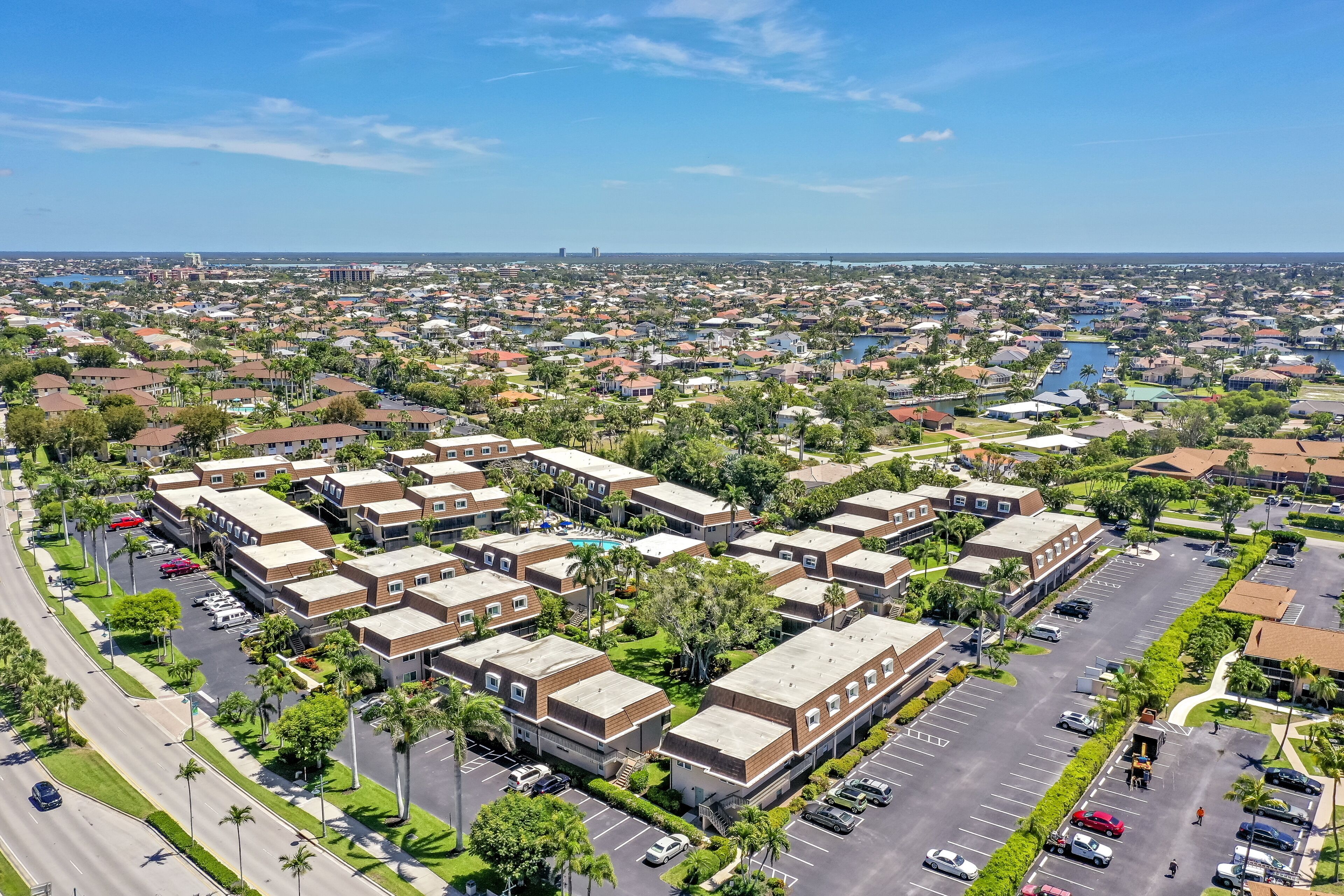 An aerial view of a residential area with multiple apartment buildings, roads, and a body of water in the background.