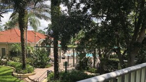Um pátio com piscina, palmeiras e um edifício com telhado vermelho.