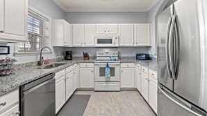Una cocina moderna con armarios blancos, un refrigerador de acero inoxidable, un microondas y un lavavajillas.
