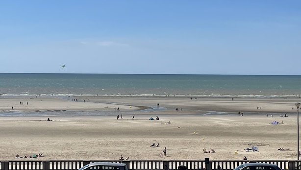 Una playa extensa con gente caminando y descansando.
