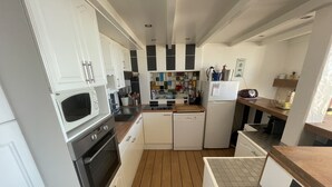 Una cocina moderna con armarios blancos, microondas, horno, lavavajillas y refrigerador.