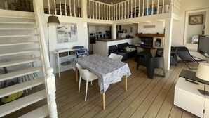 Amplia sala de estar con mesa de comedor, sofás y una cocina al fondo.