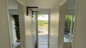 Un estrecho pasillo con piso de madera que conduce a un patio al aire libre.