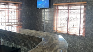 A modern interior with a marble counter, a mounted TV, and decorative windows. - Sunrise hotels  (Owerri)