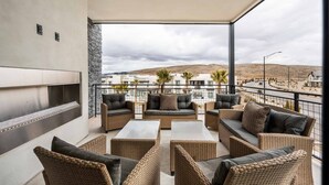 Ein Balkon mit Rattanmöbeln, einem Flachbildfernseher und Blick auf eine Wüstenlandschaft.