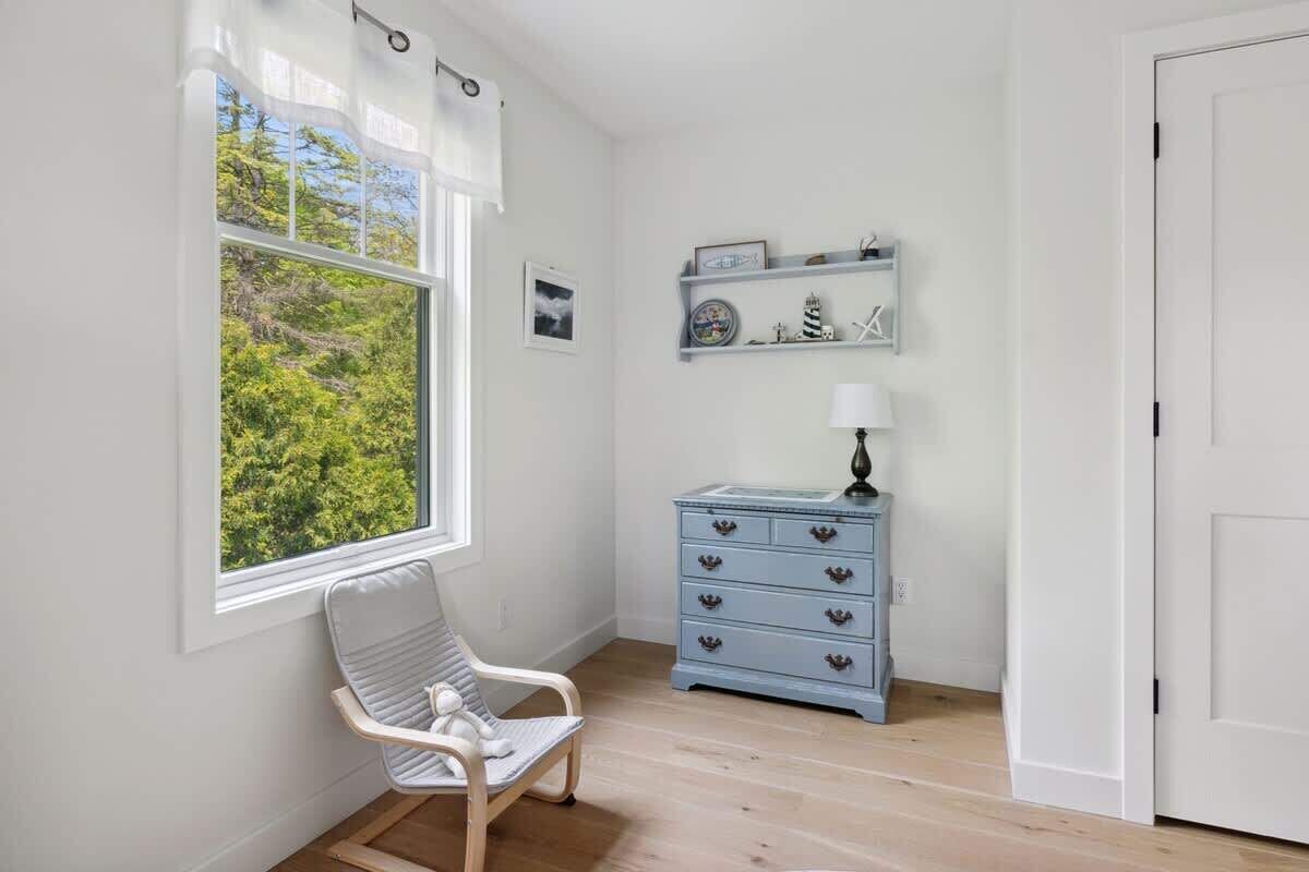 A room with a window, a chair, a dresser, and a door.