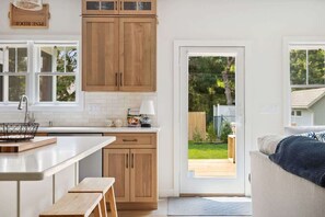 Una cocina con armarios de madera, encimera blanca y un banco.