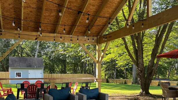 An outdoor covered patio with wicker furniture and string lights. - Westerly Retreat (Westerly)