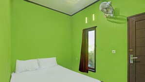 A room with a bed, a window with curtains, a door, and a wall-mounted fan.