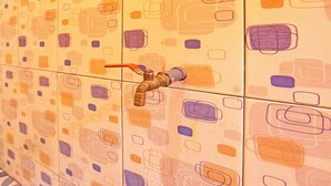 A tiled wall with a water spigot.