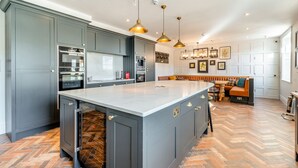 Una cocina moderna con armarios grises, una isla grande, electrodomésticos de acero inoxidable y un piso con patrón de espiga.